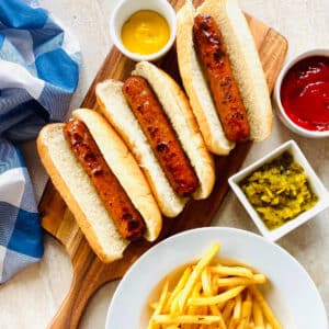 air fryer chicken sausage recipe in buns with ketchup, relish, mustard and a side of french fries.