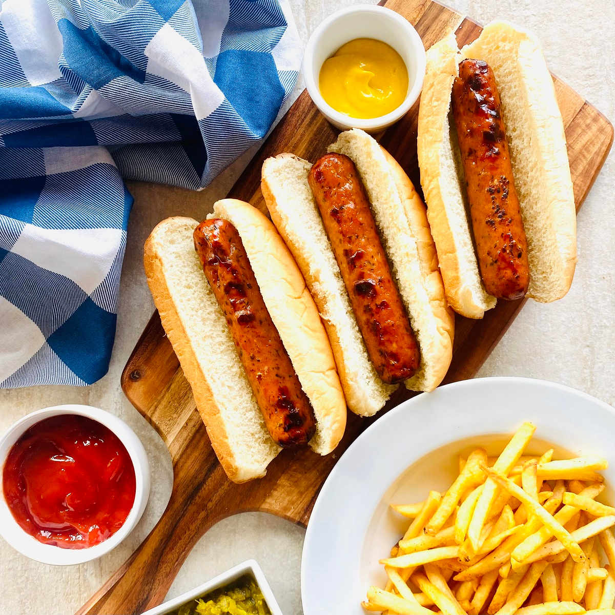 chicken sausage in buns with ketchup, relish, mustard and a side of french fries.