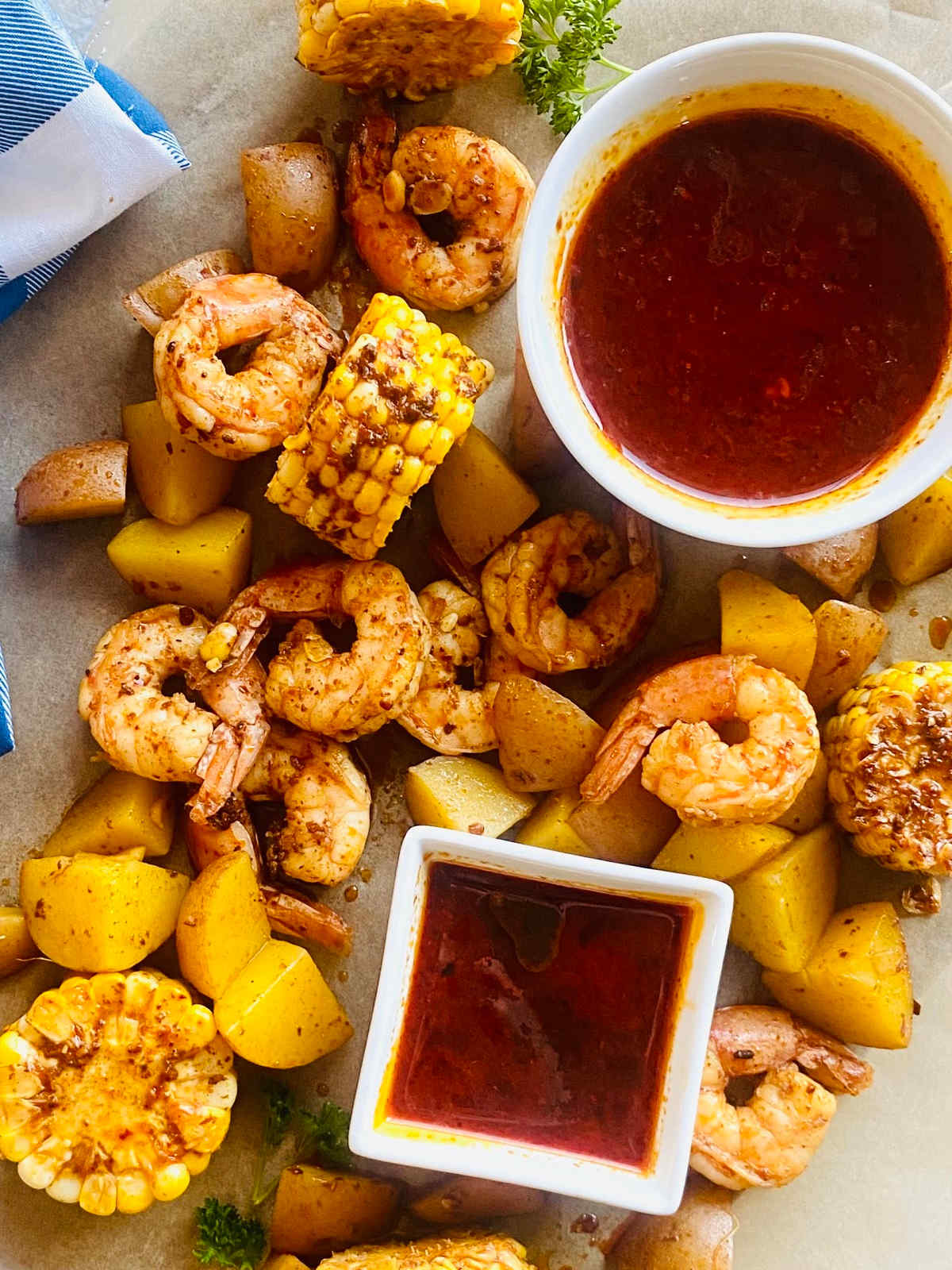 seafood boil sauce in a dish surrounded by shrimp, corn and potatoes in the seafood boil sauce.
