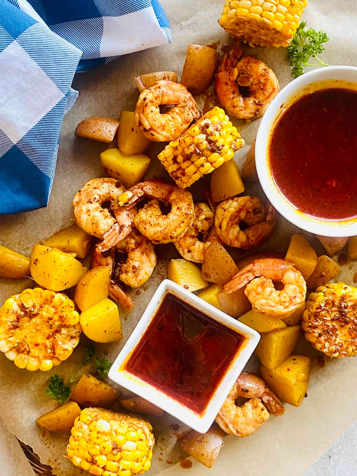 seafood sauce in a dish surrounded by shrimp, corn and potatoes in the seafood boil sauce.