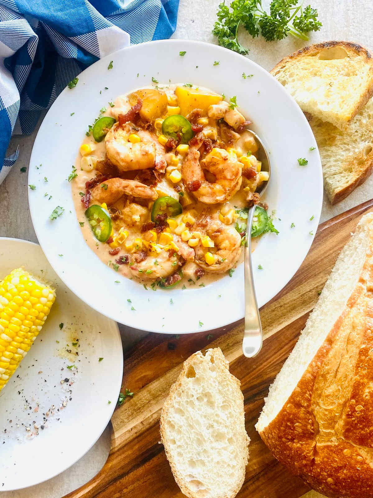 shrimp and corn bisque in a dish next to corn and bread.